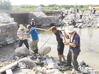 邢台县北小庄四位上了年岁的老人合力抬着一块石头