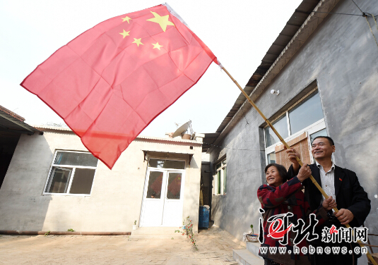 10月1日早晨,威县张营乡从容村64岁的贫困户柴素群和驻村干部一起在新房前挂国旗。 10月1日早晨,威县张营乡从容村64岁的贫困户柴素群和驻村干部一起在新房前挂国旗。